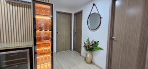 A hallway with a refrigerator, a mirror, and a vase with flowers.