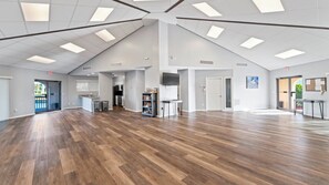 Un interior espacioso con techo alto, piso de madera y una zona de cocina.