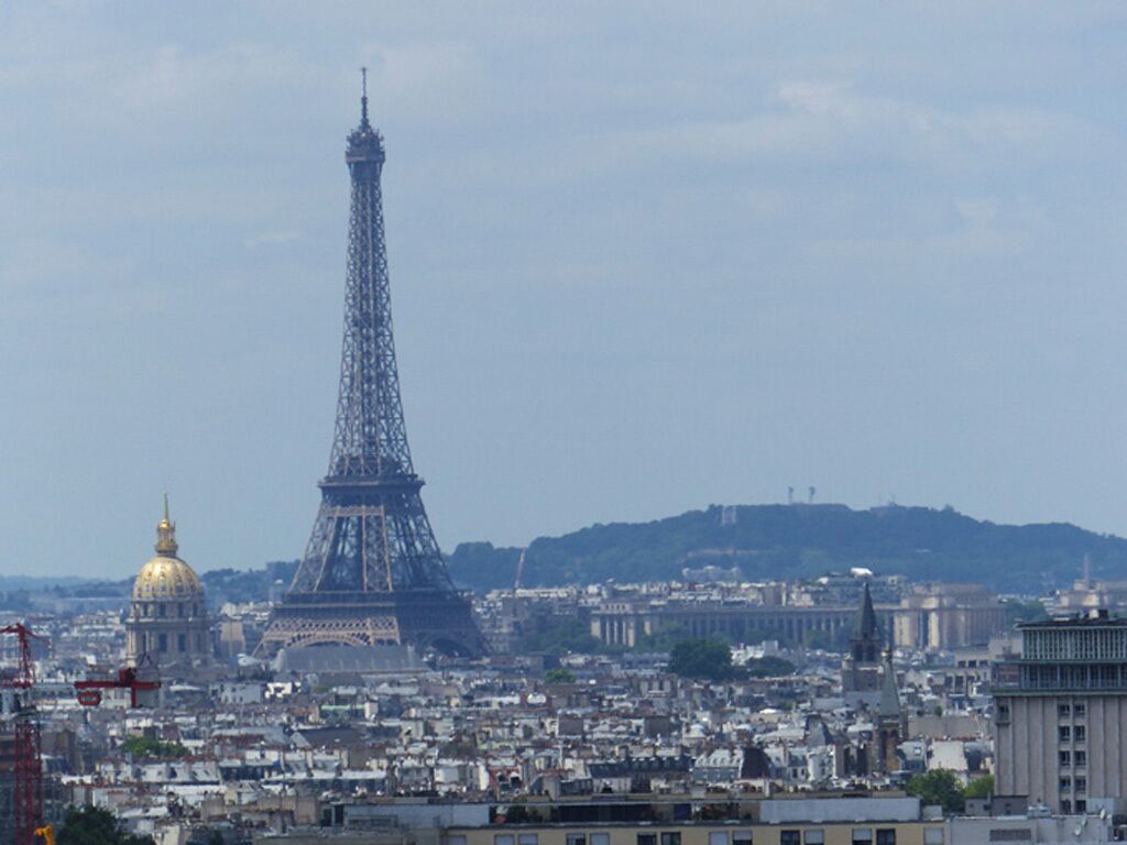 Kaupunkikuva, jossa näkyy Eiffel-torni, suuri kupoli ja taustalla kukkula.