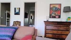 Ein Wohnzimmer mit einer Couch, einem Holzschrank und einem Bild an der Wand.