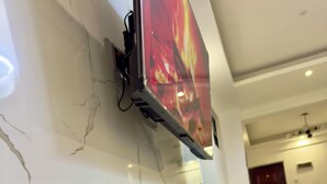Ett modernt vardagsrum med en platt-TV som är monterad på en vit vägg med marmorimitation, en blå bänk och en vit TV-möbel.