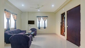 Ein Wohnzimmer mit einer Sofagarnitur, einem Couchtisch, einem Flachbildfernseher und einem Deckenventilator.