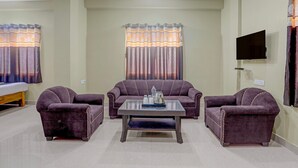 Ein Wohnzimmer mit einer Couch, zwei Sesseln, einem Couchtisch und einem flachbildfernseher an der Wand.