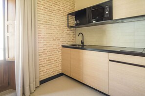 Una cocina con microondas negro, un lavabo y armarios de colores claros.