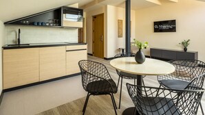 A modern kitchen with a microwave, cabinets, and a dining area with a round table and wire chairs. - Housing Fana by Sharing Co 3PAX (Málaga)