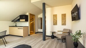 A modern living room with a sofa, a dining table, and a kitchen area with a built-in stove. - Housing Fana by Sharing Co 3PAX (Málaga)