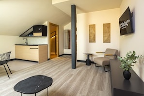 Ein modernes Wohnzimmer mit Sofa, Esstisch und Küchenzeile mit Einbauherd.