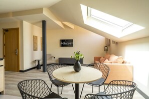 A modern living room with a skylight, a dining area with a round table and chairs, a sofa, and a TV mounted on the wall. - Housing Fana by Sharing Co 3PAX (Málaga)