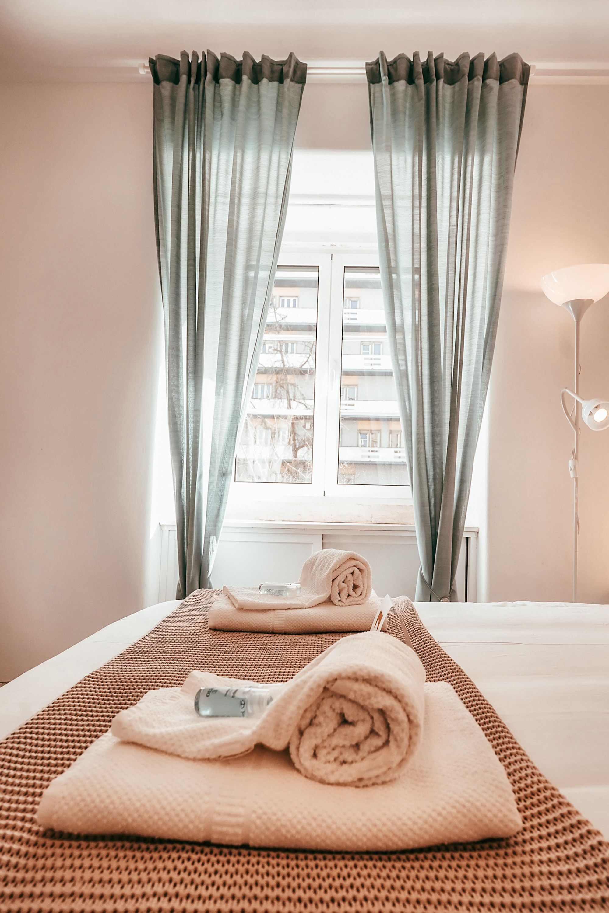 A hotel room with a bed, a window, and curtains.