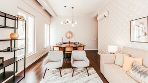 A modern living room with a dining area, a sofa, a coffee table, a bookshelf, and a chandelier. - Elegant Sophisticated Campo Ourique by GT House (Lisbon)