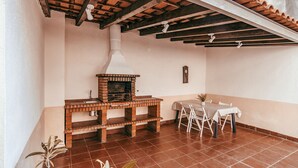 A kitchen with a brick oven, a dining table with chairs, and a tiled floor. - Alcantara Terrace by GT House (Lisbon)