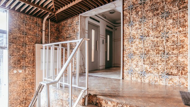A staircase with metal railings leading to a landing, a tiled wall with a pattern, and a doorway to another room. - Alcantara Terrace by GT House (Lisbon)