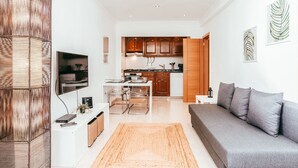 A modern living room with a grey sofa, a wooden cabinet, and a TV mounted on the wall. - Alcantara Terrace by GT House (Lisbon)