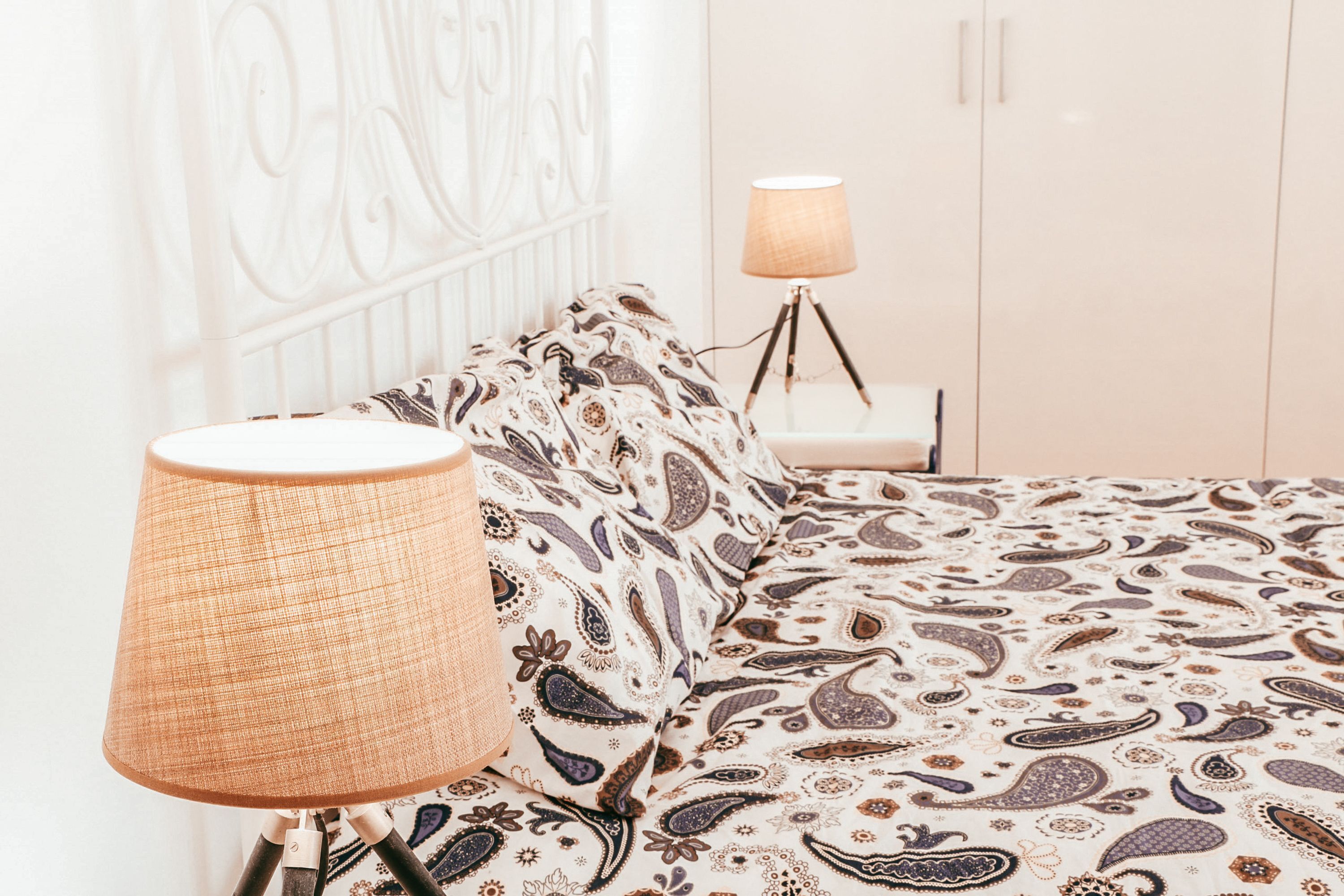 Un lit avec une couvre-lit à motifs, une lampe sur une table de chevet et une armoire dans la pièce.