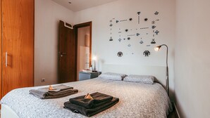 A bedroom with a bed, a wardrobe, a nightstand, a lamp, and a wall with pixel art. - Central Typical Lisboa by GT House (Lisbon)