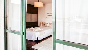 A hotel room with a bed, a hanging light fixture, a wall with text, and a view through a window. - Amadora Terrace View By Gt House (Amadora)