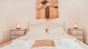A neatly made bed with white linens, two bedside tables with lamps, and a wall hanging above. - Altura Beach Villa by GT House (Castro Marim)