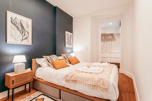 A bedroom with a bed, bedside tables, wall art, and a wardrobe. - Chic Elegant Lapa By GT House (Lisbon)