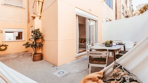 Un espacio al aire libre acogedor con una mesa, sillas y un sofá con cojines.