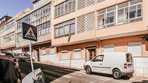 Un edificio con varias ventanas, una señal de paso para peatones y una furgoneta estacionada.