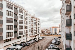 A multi-story residential building with balconies, a parking lot, and a view of a distant cityscape. - Modern Elegant 2 Bedroom in Amadora by GT House (Amadora)