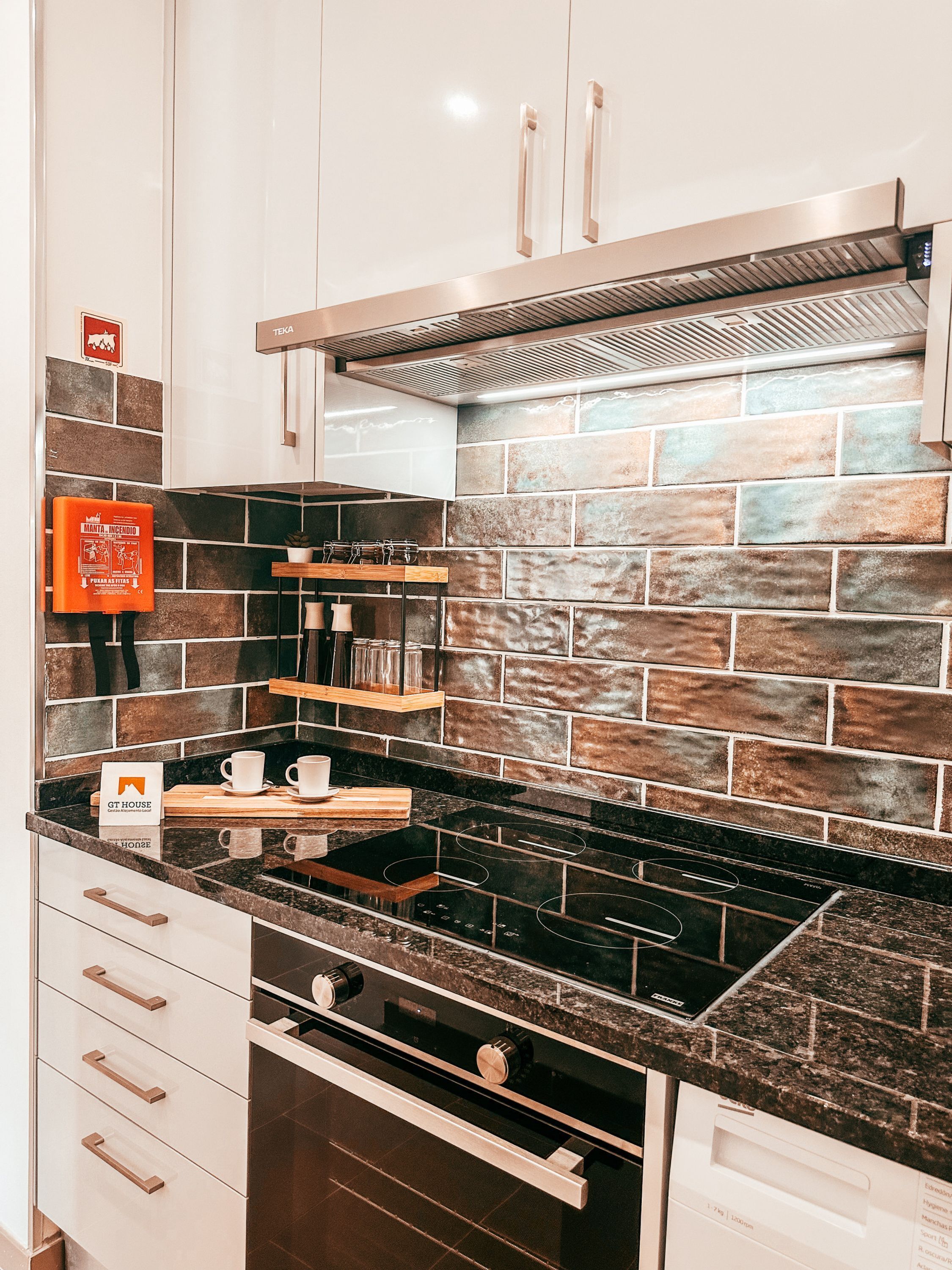 A kitchen with white cabinets, a black stove, and a backsplash with brown and beige tiles.