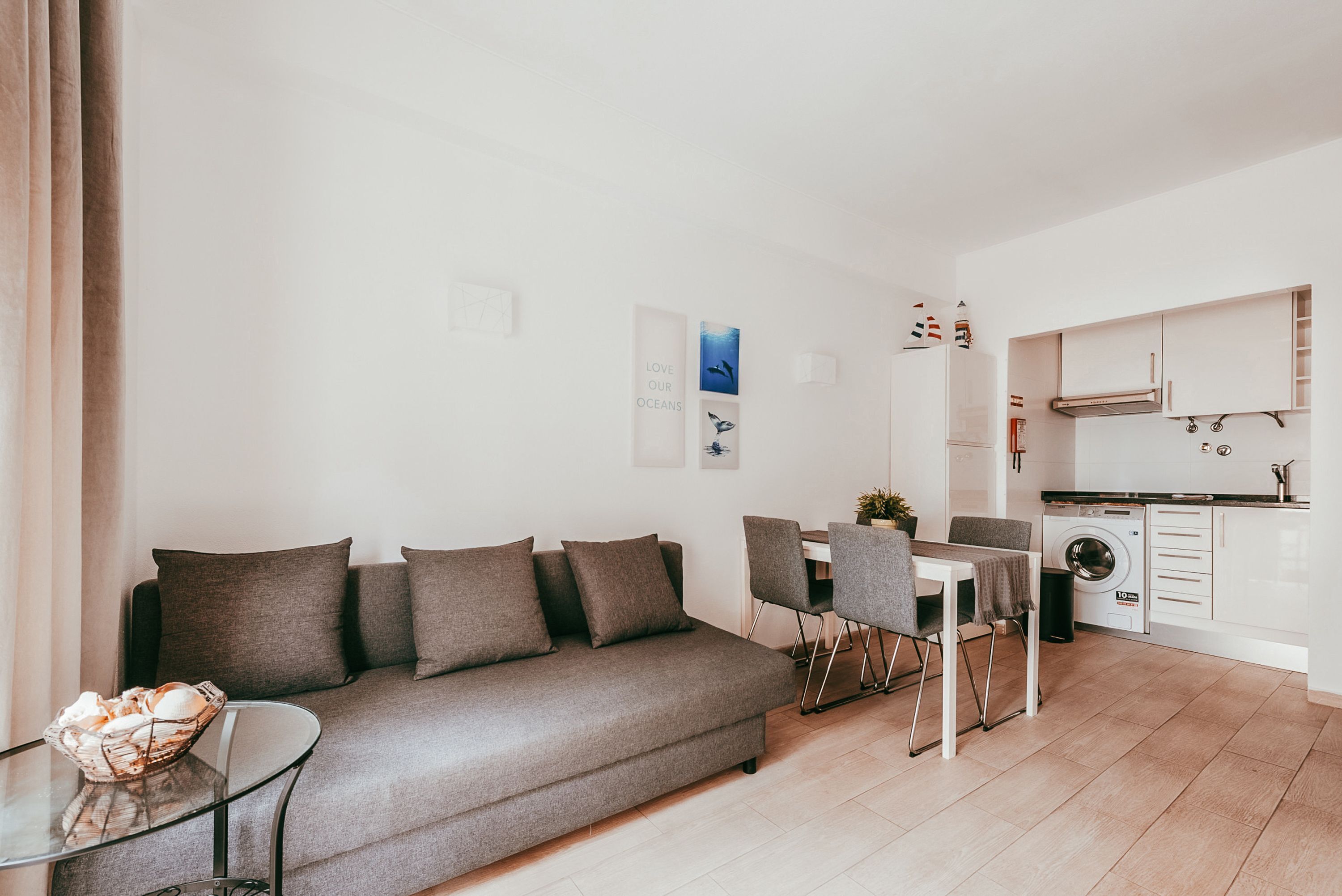 Ein modernes Wohnzimmer mit einer Couch, einem Glastisch und einem Essbereich mit Stühlen.
