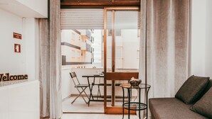 A modern interior with a sofa, a small table, a chair, and a glass door leading to an outdoor balcony. - Beach House By Gt House (Silves)