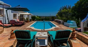 Un espace piscine équipé de chaises longues, d’une table et de parasols.