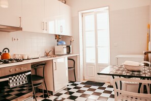 A kitchen with a checkered floor, white cabinets, a stove, and a microwave. - Kalathos House 2 With Terrace By Gt House (Lisbon)