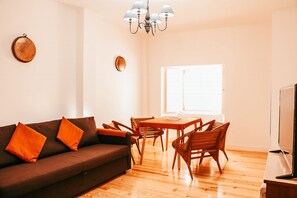 A living room with a sofa, wooden chairs, a dining table, and a TV. - Kalathos House 2 With Terrace By Gt House (Lisbon)