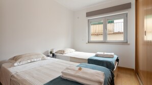 Une chambre avec deux lits, une fenêtre et une armoire.