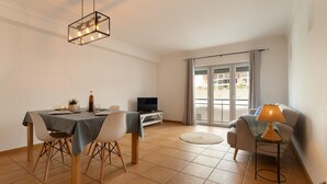 Un coin repas avec une table dressée pour deux personnes, un téléviseur et un canapé avec une lampe.