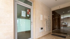 Une entrée d’immeuble avec une porte vitrée, des murs carrelés, un détecteur d’incendie et une fente pour le courrier.