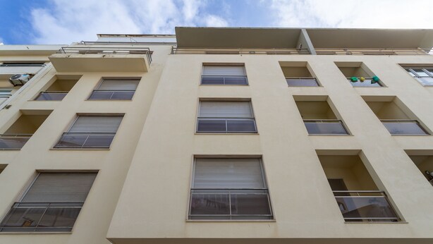 Un immeuble à plusieurs étages, doté d’une façade beige, de nombreuses fenêtres et de balcons.