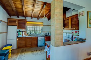 A kitchen with wooden cabinets, a built-in dishwasher, and a window. - Papoula Apartment in Quinta Velha by GT House (Portimão)