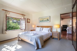 A hotel room with a bed, bedside lamps, a painting, a window with curtains, and a view of greenery outside. - Charming House and Terrace By Gt House (Sintra)