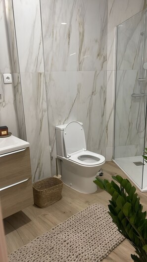 Un bagno moderno con il water, doccia e pavimento in legno.