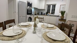 A dining area with a white table set for four, surrounded by chairs. - Goleg Boutique Apartment By Gt House (Golega)