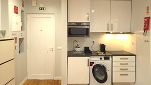 A compact kitchen with a washing machine, microwave, and a sink. - Sesimbra Terrace Escape By Gt House (Sesimbra)