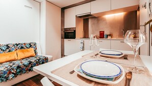 Uma cozinha moderna com armários brancos, forno embutido e micro-ondas.