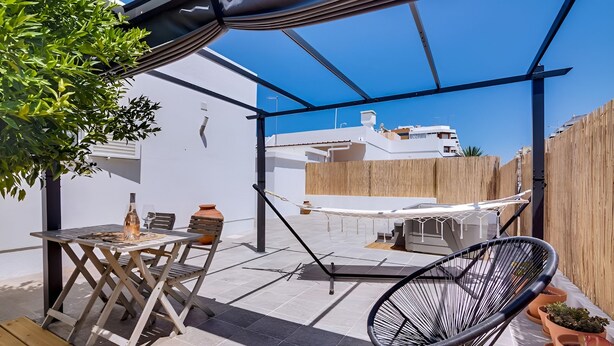 Eine Terrasse mit Tisch, Stühlen, einer Hängematte und Kübelpflanzen.