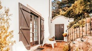A courtyard with a white chair, a wooden door, and a stone wall. - Oliveira s Houses By Gthouse (Sintra)