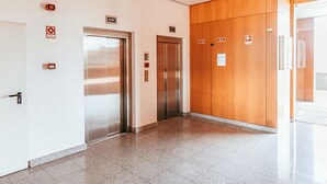 An elevator area with two elevators, a door with a lock, and a wooden panel wall. - Trendy Apartment River View By Gthouse (Lisbon)