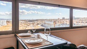 A dining table with plates, a wine glass, and a cup, set against a window with a city view. - Trendy Apartment River View By Gthouse (Lisbon)