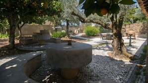 An outdoor courtyard with stone planters, a central stone table, and surrounding trees. - Bonjardim Boutique Villa by Gt House (Serta)