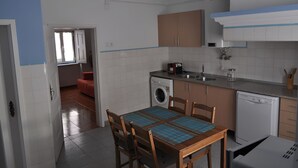 Une cuisine équipée d’un lave-linge, d’un évier et d’un coin repas avec une table et des chaises.