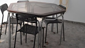 Une table avec un plateau en verre, quatre chaises, une petite plante et un objet fixé au mur.
