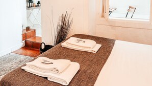 Un dormitorio con cama, lámpara colgante, ventana y vista al exterior.