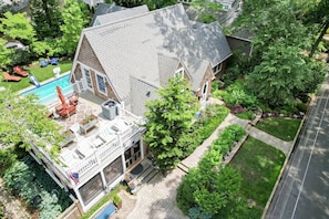 A two-story house with a covered patio, a swimming pool, and a well-maintained garden. - Quiet Pines Escape | Private Pool | BBQ | Beach (Rehoboth Beach)
